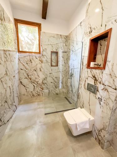 a bathroom with a toilet and a stone wall at Just Heaven Apartments in Matemwe