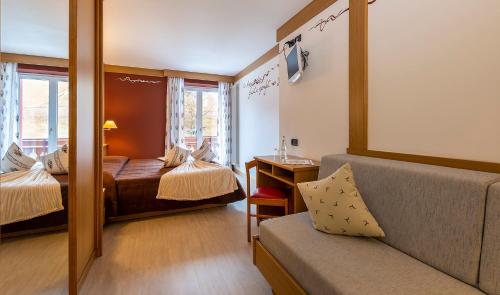 a hotel room with two beds and a couch at Hotel La Serenella in Moena