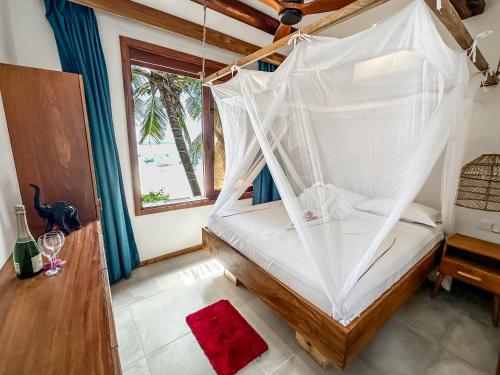 a bedroom with a bed with a mosquito net at Just Heaven Apartments in Matemwe