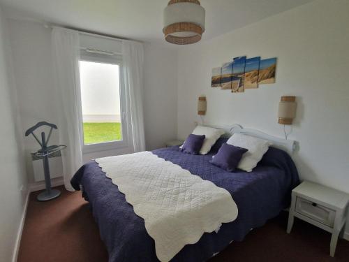 Un dormitorio con una cama azul y blanca y una ventana en Flat in Brittany near Sandy Beach & Golf, en Saint-Cast-le-Guildo