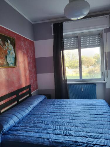 a bedroom with a bed with a blue blanket and a window at Casa Le Vele in Bordighera