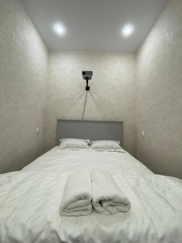 um quarto com uma cama branca com duas toalhas em Домик 1 Kok Tobe Village em Almaty