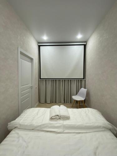 una camera con un grande letto bianco e una sedia di Уютный домик для идеального отдыха a Almaty