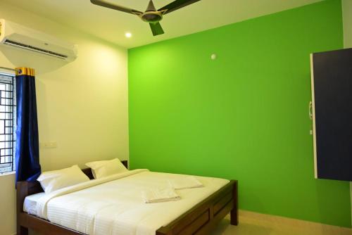 a green bedroom with a bed with a ceiling fan at Sea View JC Villa in Kottakupam