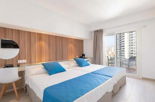 a large bedroom with a large bed with blue pillows at Hotel Rosamar in Benidorm