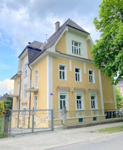 una casa amarilla con una puerta delante de ella en Stilvolle Wohnungen im Villenviertel Villachs, en Villach