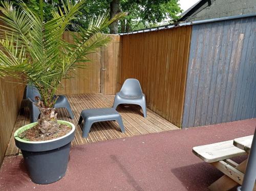 un patio con 2 sillas, una maceta y un banco en L'étable La Villa St Martin, en Pontorson
