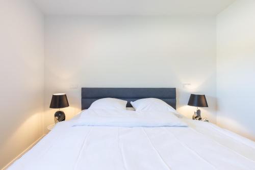 a bedroom with a large white bed with two lamps at Georgs Huis in Neukirchen