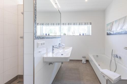 a white bathroom with a sink and a tub at Georgs Huis in Neukirchen