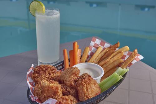 a basket of fried chicken and french fries with a glass of water at City Express by Marriott Cancun Aeropuerto in Cancún