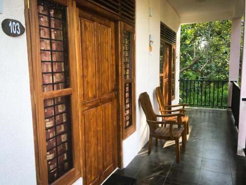 un porche con una puerta de madera y una silla en Kings Villa, en Habarana