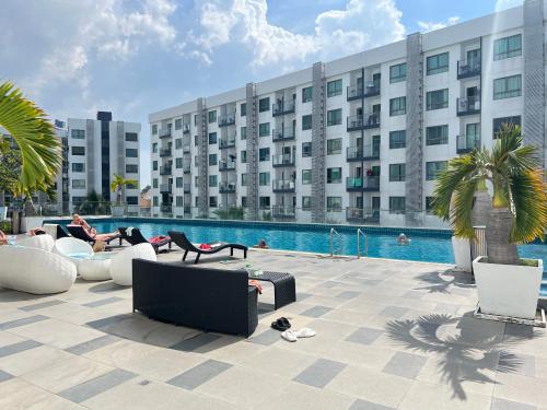 a large building with a pool and people sitting on couches at Arcadia Beach Resort Condominium in Pattaya South