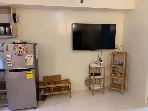 cocina con nevera y TV en la pared en Brenthill Condo (Sandstone Unit), en Baguio