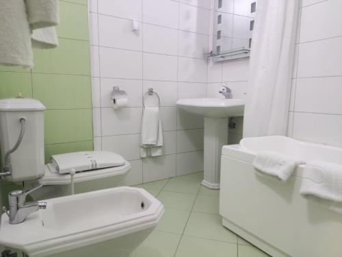 a white bathroom with a toilet and a sink at Hotel & Restaurant White City in Berat