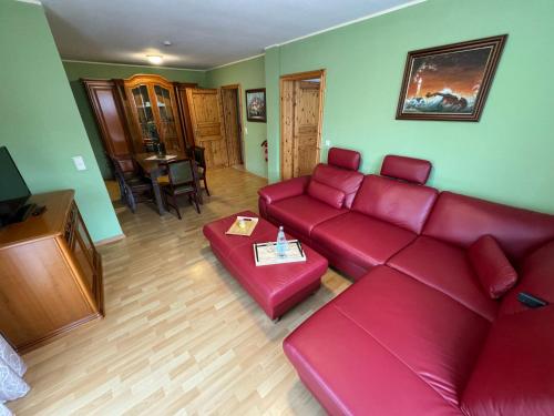 a living room with a red couch and a table at Hotel Garni Seeschlösschen in Kolpinsee