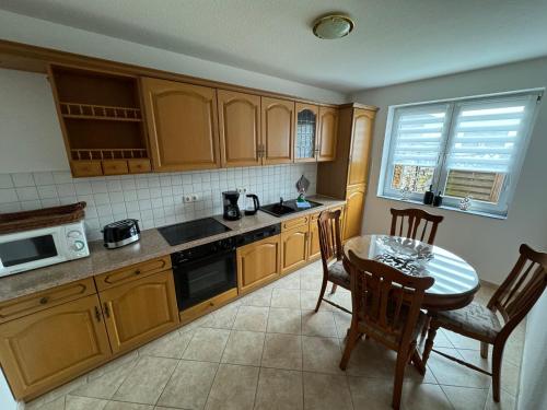 a kitchen with wooden cabinets and a table and chairs at Hotel garni SEESCHLÖSSCHEN in Kolpinsee