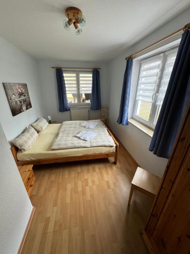 a bedroom with a bed and two windows at Hotel garni SEESCHLÖSSCHEN in Kolpinsee