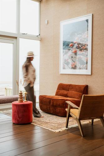 a man walking through a living room with a couch at Strandhotel Zoomers in Castricum