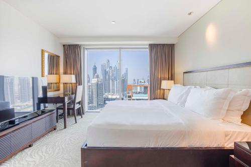 a bedroom with a bed and a desk and a window at Daniels 1BR at Address Marina High Floor with Marina View in Dubai