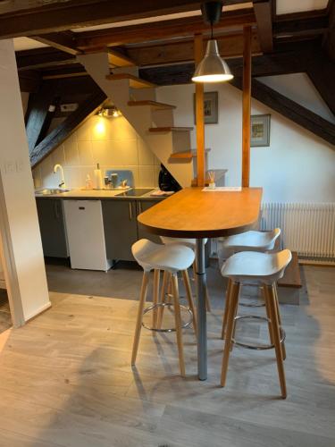une cuisine avec une table en bois et quatre tabourets dans l'établissement Appartement Duplex 2a Rue d'Alspach, à Colmar