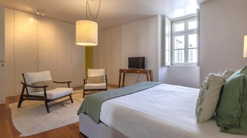 a bedroom with a bed and two chairs and a television at LovelyStay - Chiado 3Bedroom Wonder in Lisbon