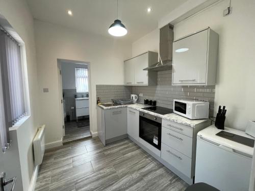 a kitchen with white cabinets and a stove top oven at Rooms Near Me - Apartment 2, Smart Tv, Free Parking in Halesowen