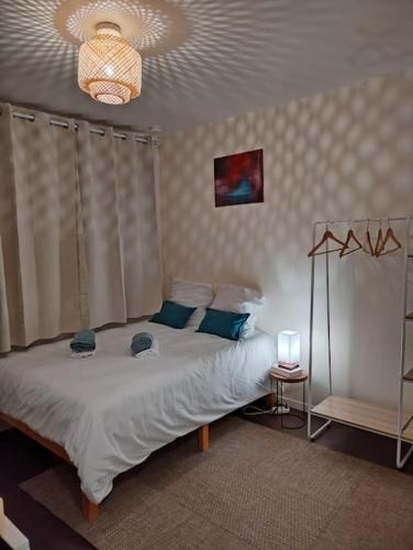 une chambre avec un lit blanc avec des oreillers bleus dans l'établissement Studio Indépendant avec terrasse proche Paris, à Épinay-sur-Seine