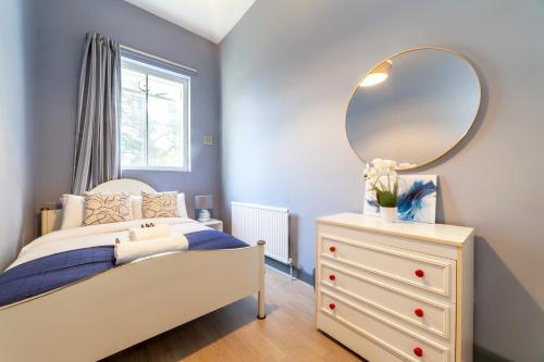 a bedroom with a bed and a mirror on a dresser at Couple's getaway 1BDR apt near Holland Park in London