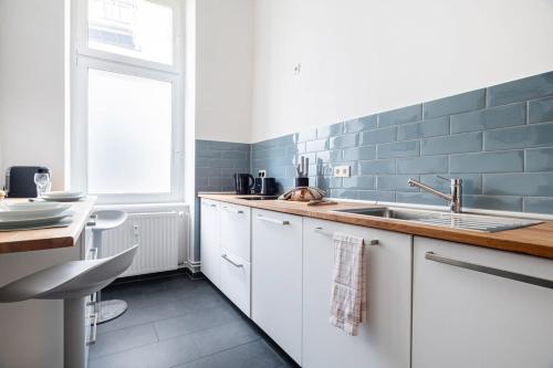een keuken met witte kasten, een wastafel en een raam bij City Apartment: Homeoffice und Erholung vereint! in Berlijn