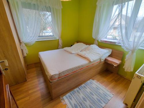 "ハルカーニャ"にあるAttila apartman Harkányの窓2つが備わるドミトリールームの小さなベッド1台分です。