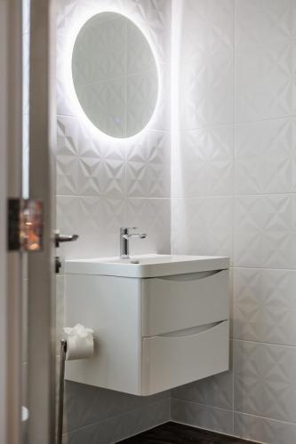 a white bathroom with a sink and a mirror at Tower House Apartments in Bournemouth