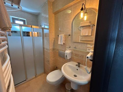 ein Badezimmer mit einem Waschbecken, einem WC und einem Spiegel in der Unterkunft Lopera Beach Hotel in Edremit