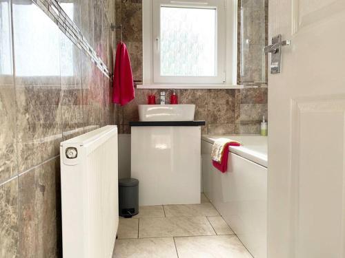 a bathroom with a sink and a toilet and a window at Modern And Vibrantly Designed Apartment in Motherwell