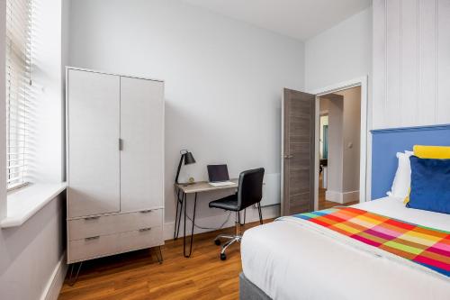 a bedroom with a bed and a desk with a computer at Tower House Apartments in Bournemouth