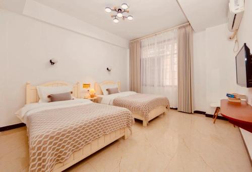 a bedroom with two beds and a tv and a window at 26 Degrees Inn in Zhangjiajie