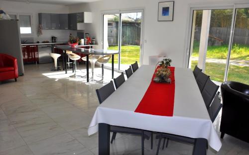 une cuisine et une salle à manger avec une table blanche et un chiffon rouge dans l'établissement Villa bord de mer, à Soulac-sur-Mer