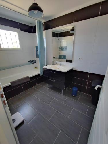 une salle de bain avec un lavabo et un grand miroir dans l'établissement Villa bord de mer, à Soulac-sur-Mer
