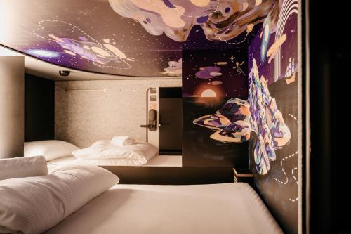 two beds in a room with a painting on the wall at Capsule Hotel - Lucerne Old Town in Luzern