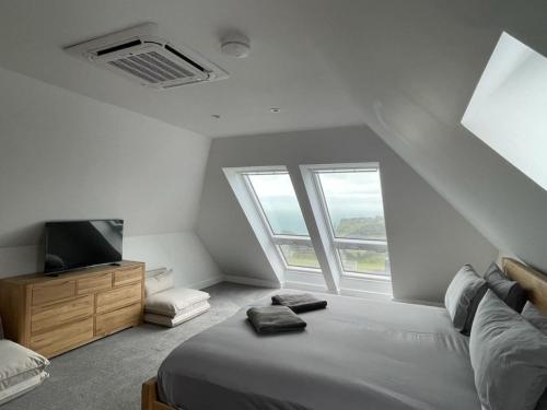 een slaapkamer met een bed, een tv en ramen bij Lancelots Breathtaking views in Tintagel