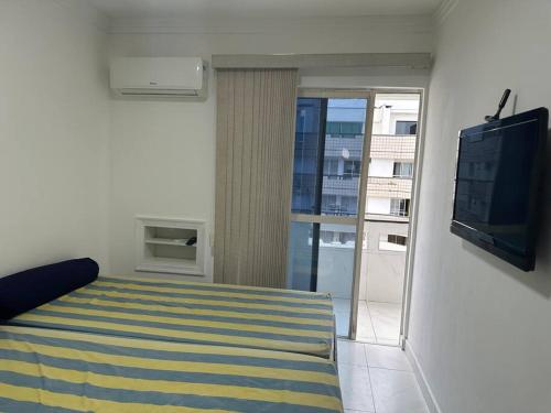 a bedroom with a bed and a flat screen tv at Ape Caiobá vznho boliche e Assoc Caixa Econômica in Matinhos