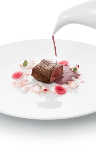 a piece of meat on a white plate with a water fountain at Il Porticciolo in Laveno-Mombello