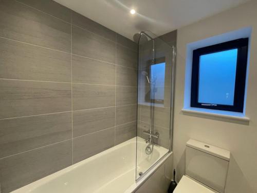 bagno con vasca, servizi igienici e finestra di Pendragon Uninterrupted coastal views a Tintagel