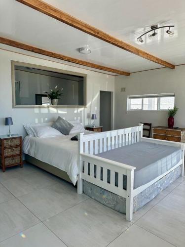 a bedroom with a large white bed and a mirror at Blue Bay Studio Bayview in Cape Town