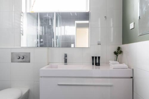 uma casa de banho branca com um lavatório e um espelho em Maddox · MADDOX: 5min Walk to Train with Netflix & Parking em Melbourne