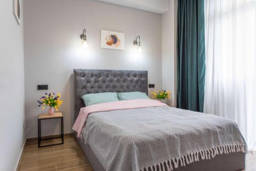 Schlafzimmer mit einem Bett mit grauem Kopfteil in der Unterkunft Apart Hotel New Line in Tbilisi City