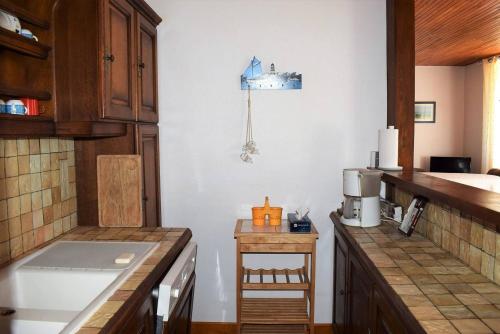 cocina con paredes blancas y armarios de madera en Maison à 100m plage de Tourony avec jardin clos à TREGASTEL - Réf 400, en Trégastel