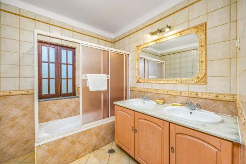 ein Badezimmer mit einem Waschbecken, einer Badewanne und einem Spiegel in der Unterkunft Villa Casa Coelho by Villa Plus in Terras Novas