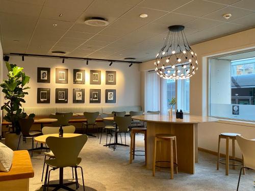 ein Restaurant mit Tischen, Stühlen und einem Kronleuchter in der Unterkunft Comfort Hotel Park in Trondheim
