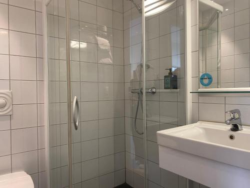 a white bathroom with a shower and a sink at Comfort Hotel Park in Trondheim