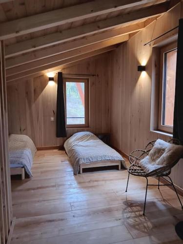 - une chambre avec 2 lits et une chaise dans l'établissement Maison Cosy 10 personnes, à Clairvaux-les-Lacs